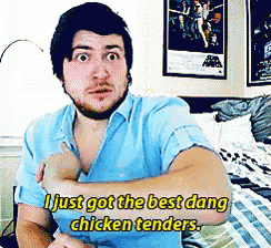 a man in a blue shirt is sitting on a bed and says i just got the best dang chicken tenders