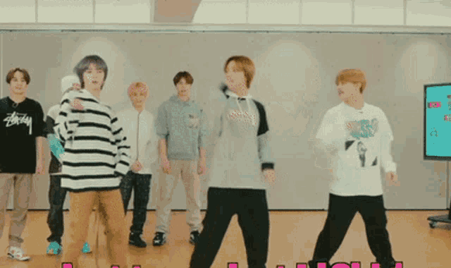 a group of young men are dancing in a room and one of them is wearing a stussy shirt .