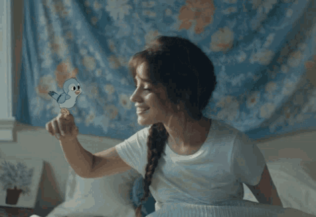 a woman in a white shirt is holding a blue bird in her hand