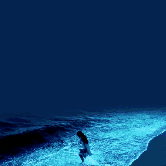 a woman in a white dress stands in the ocean