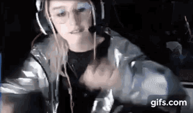 a woman wearing headphones and a jacket is sitting in front of a computer screen .