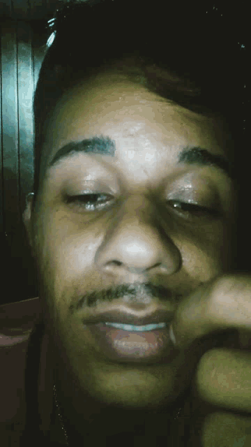 a close up of a man 's face with his hand on his nose