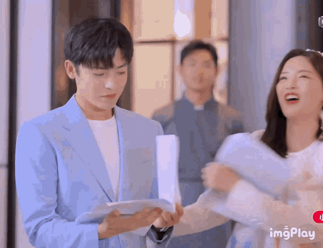 a man in a blue suit is holding a piece of paper in front of a woman