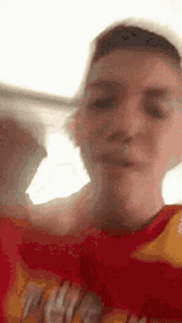 a young man wearing a red shirt and a yellow shirt is holding a bag of chips .