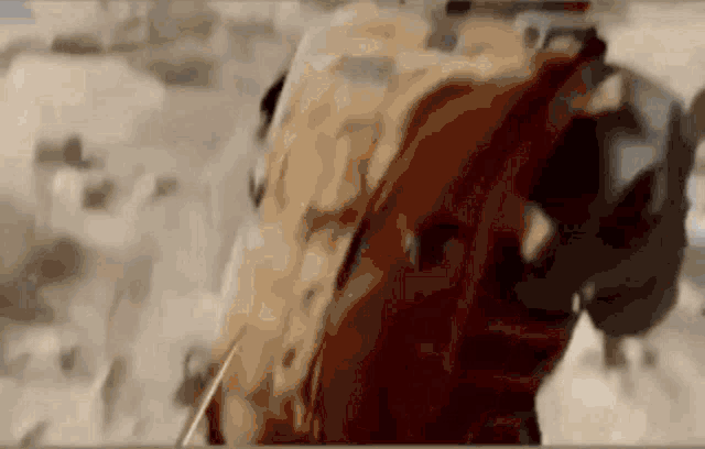 a man in a military uniform is walking through the desert with a backpack .