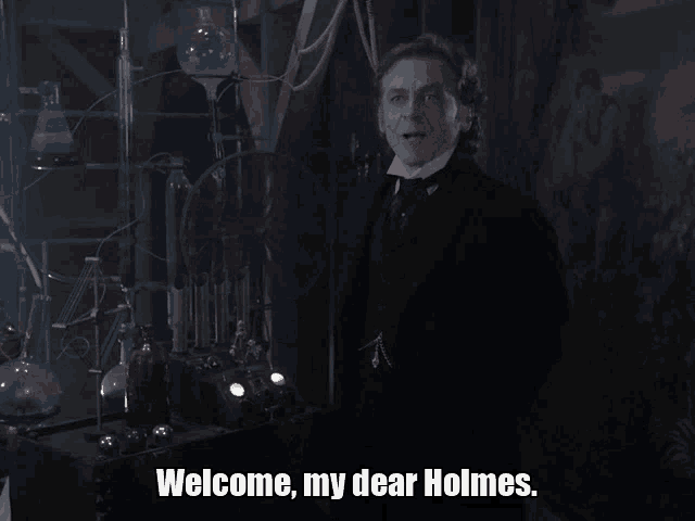 a man in a suit and tie says welcome my dear holmes in a dark room