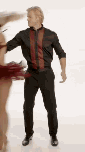 a man in a black shirt and black pants is dancing with a woman