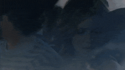 a man and a woman are sitting in a car with the woman covering her face