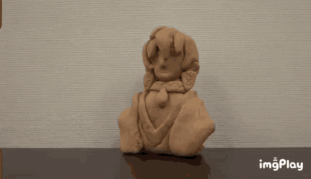 a clay sculpture of a woman is sitting on a table next to the words imgplay