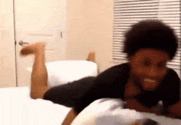 a man is laying on his stomach on a bed with his legs up .
