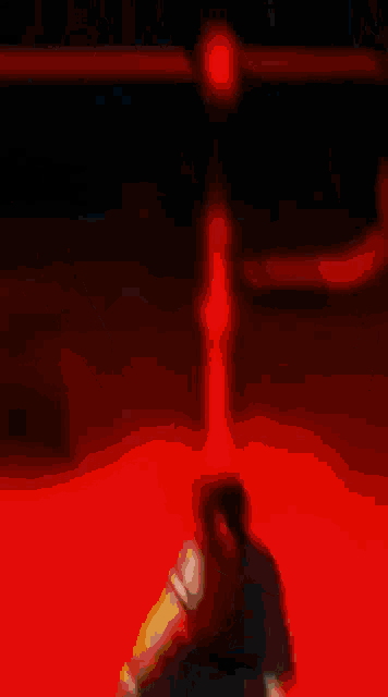a man in a kimono is standing in a dark room with a red light behind him