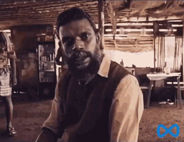 a man with a beard is in a room with a blue infinity symbol
