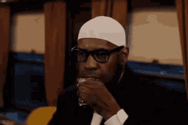 a man wearing a white hat and glasses is drinking a cup of coffee .