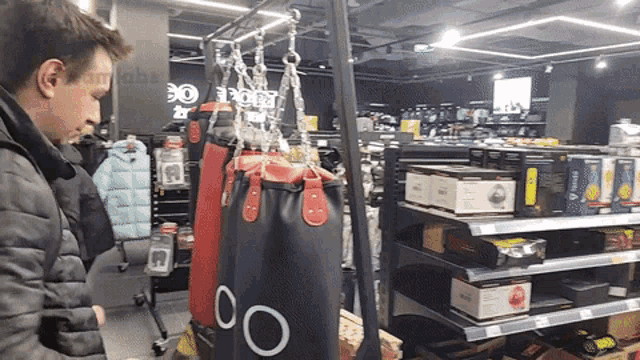 a man is looking at a punching bag in a store that says 00 on it