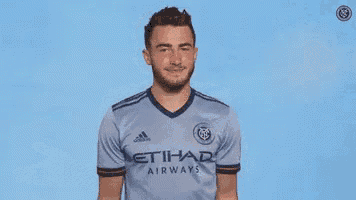 a man wearing a blue etihad airways jersey is shrugging his shoulders .