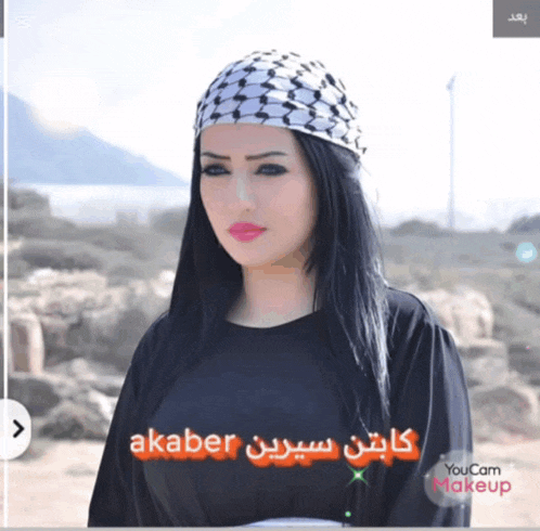 a woman wearing a head scarf and a black shirt with the words akaber on the bottom
