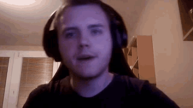a man wearing headphones and a black shirt is looking at the camera