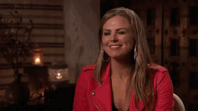 a woman in a red leather jacket is smiling