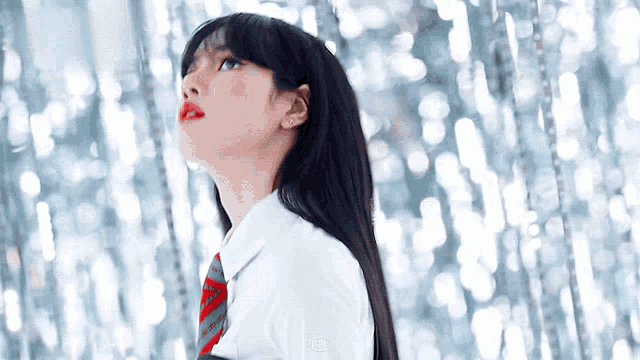 a woman with long black hair and red lipstick is wearing a white shirt and a red tie .
