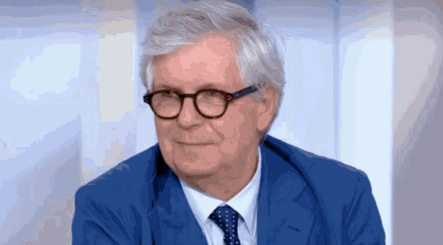 a man wearing glasses and a blue suit and tie