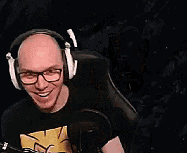 a man wearing headphones and glasses is sitting in front of a microphone .