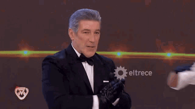 a man in a tuxedo is being touched by a woman in a white shirt with eltrece written in the corner