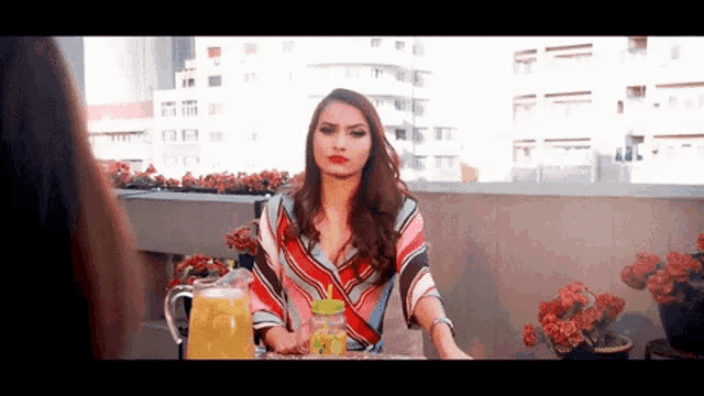 a woman is sitting at a table with a pitcher of orange juice
