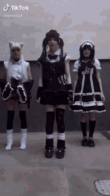 a group of three girls are standing next to each other wearing different dresses .