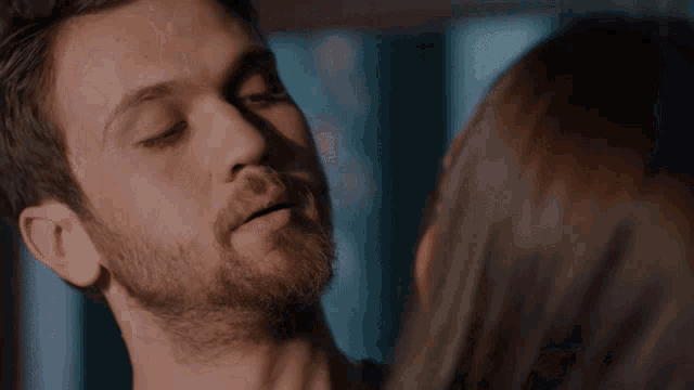 a man and a woman are kissing and the woman is looking at the man