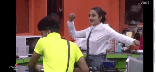 a man and a woman are dancing in a kitchen with their arms in the air .