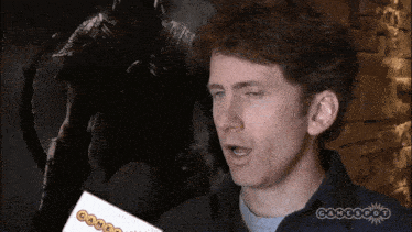a man holds a piece of paper that says gamespot on it