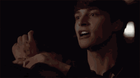 a close up of a person 's face with their hands on their wrists