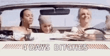 three women are driving a convertible car with the words `` 4 days bitches '' written on the side .