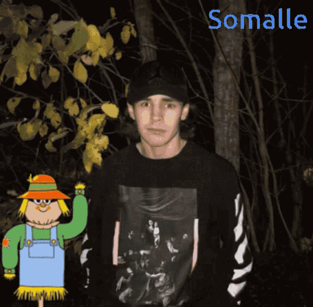 a man in a black shirt stands next to a scarecrow with the name somalle on the bottom