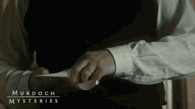a man is holding a piece of paper with murdoch mysteries written on it