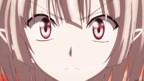 a close up of a girl 's face with red eyes and a very angry look on her face .