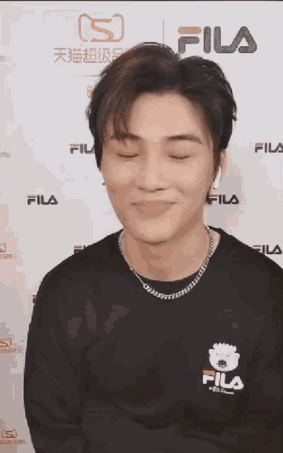a young man wearing a black fila shirt is smiling