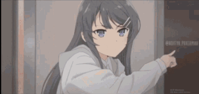 a girl in a hoodie is pointing at a sign that says ' hatsuya peacumaru '