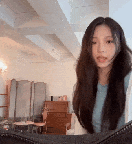 a woman with long hair is looking at herself in the mirror