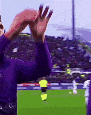 a soccer player in a purple jersey is waving at the camera
