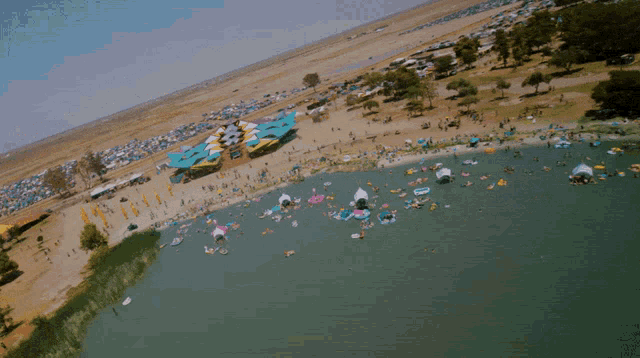 an aerial view of a lake filled with rafts and tents