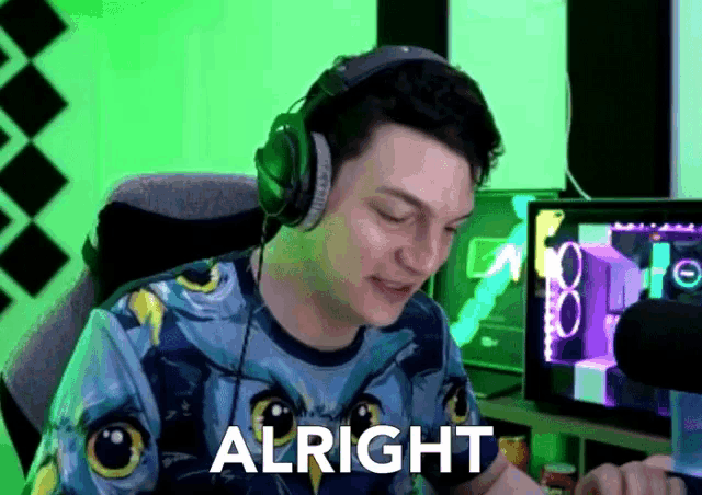 a man wearing headphones says " alright " while sitting in front of a computer