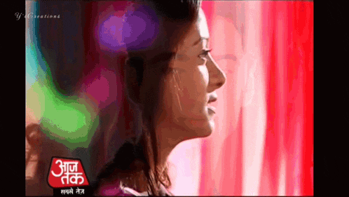a woman is standing in front of a red curtain and a sign that says " आज तक " on it