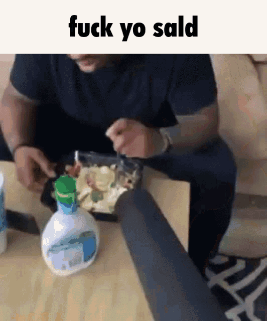 a man is sitting at a table eating a salad with a caption that says " fuck yo sald "