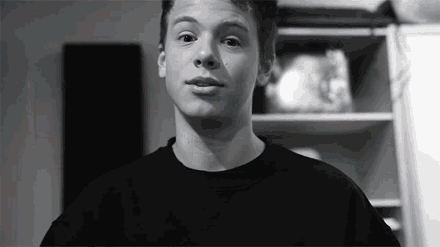 a black and white photo of a young man wearing a black sweater