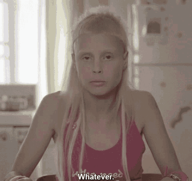 a blonde woman wearing a pink tank top that says whatever