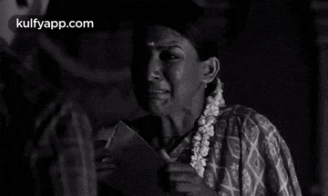 a woman is crying while holding a piece of paper in her hand .