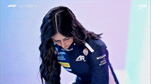 a woman in a williams racing suit is looking down