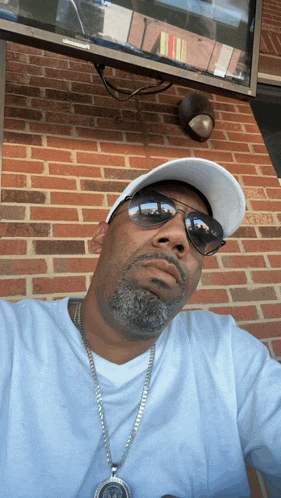 a man wearing sunglasses and a white hat looks at the camera