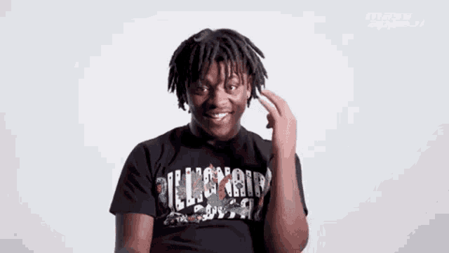 a young man with dreadlocks is making a funny face while wearing a black shirt .